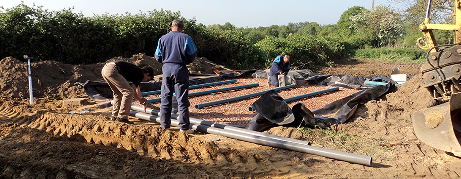 3 hommes installent un filtre  sable dans une cour