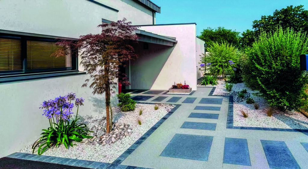 Entrée de maison contemporaine en béton poreux avec pas japonais et massif planté