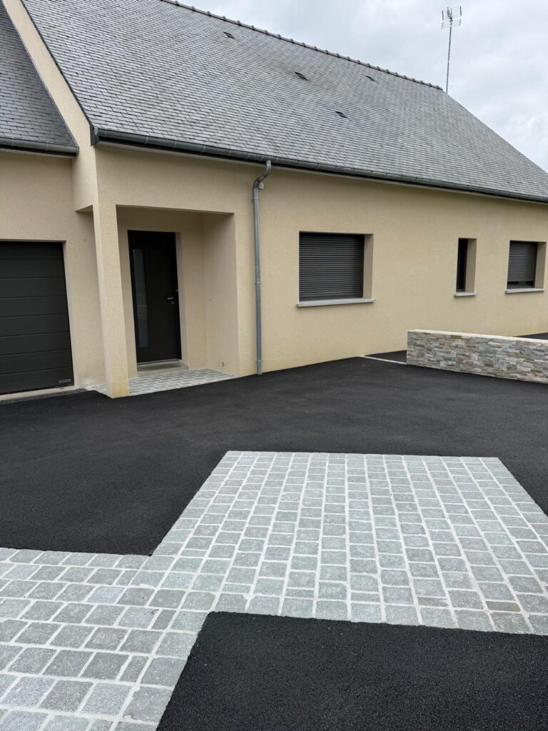 Cour en enrobé noir et pavage en pierre naturelle grise devant une maison au Pertre (35)