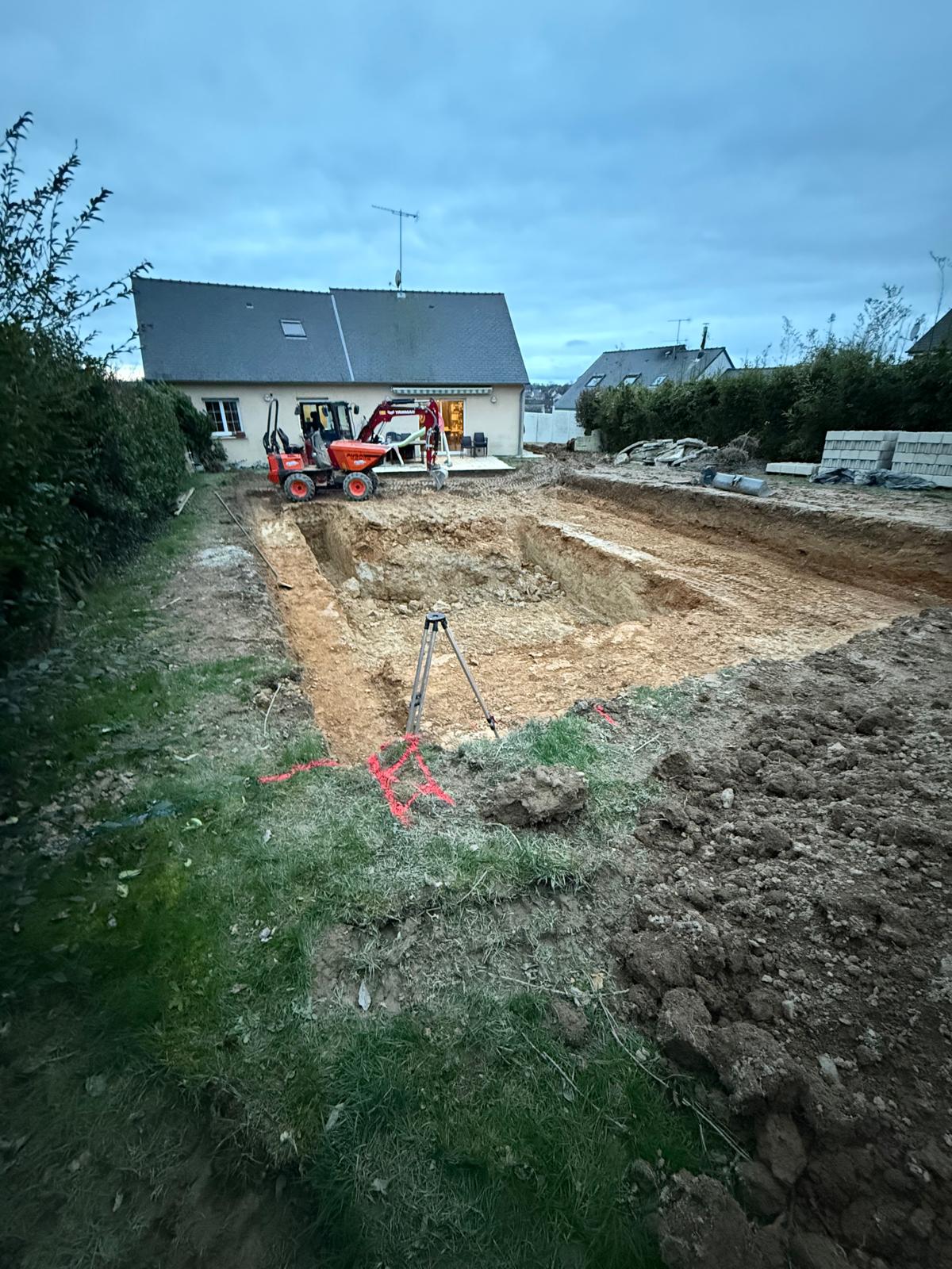 Fouille de terrassement devant une maison, avec mini-pelle et niveau laser