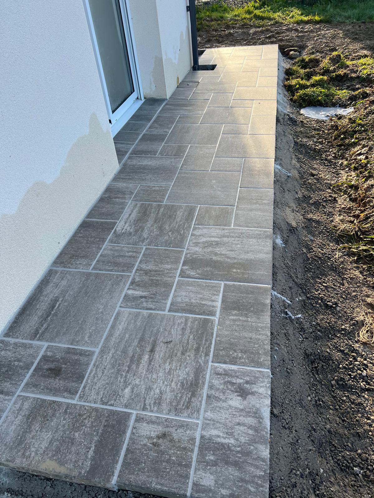 Terrasse étroite en dalles grises le long d'une maison neuve