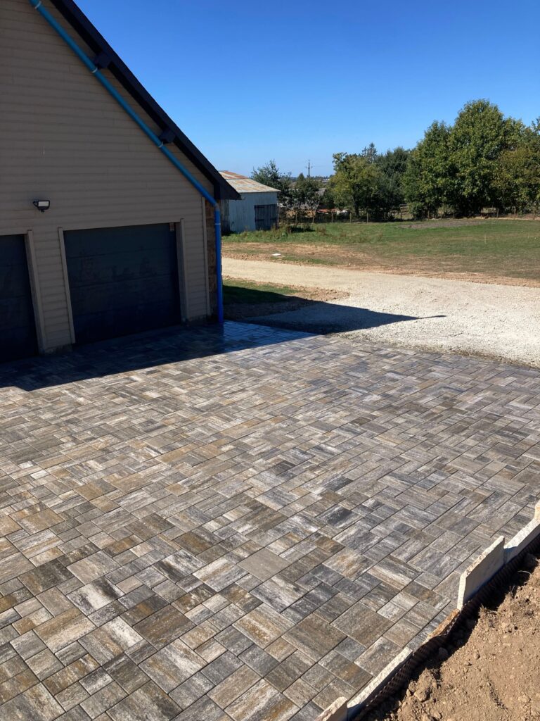 Pavés drainants en pose sauvage devant les garages d'une longère à Fougerolles-du-Plessis