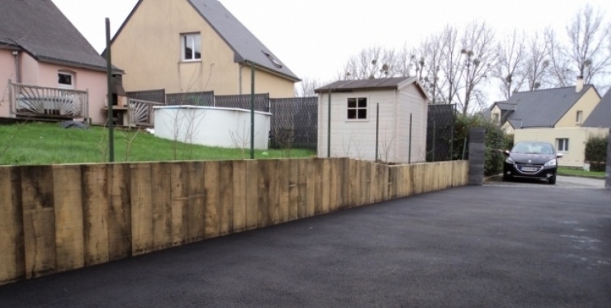 Traverses en bois posées à la verticale le long d'une cour en enrobé