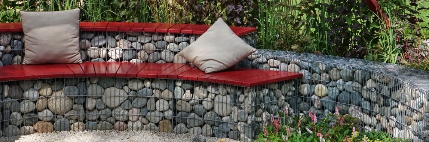 Banc en gabion garni de coussins dans un jardin