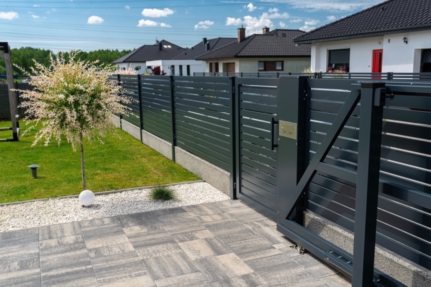 Clôture en aluminium gris avec portillon, en bordure d'une cour dallée
