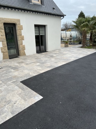 Terrasse en dalles de travertin prolongée par une cour en enrobé noir