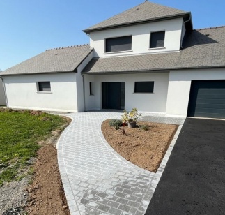 Allée pavée menant à l'entrée d'une maison, reliée à une cour en enrobé